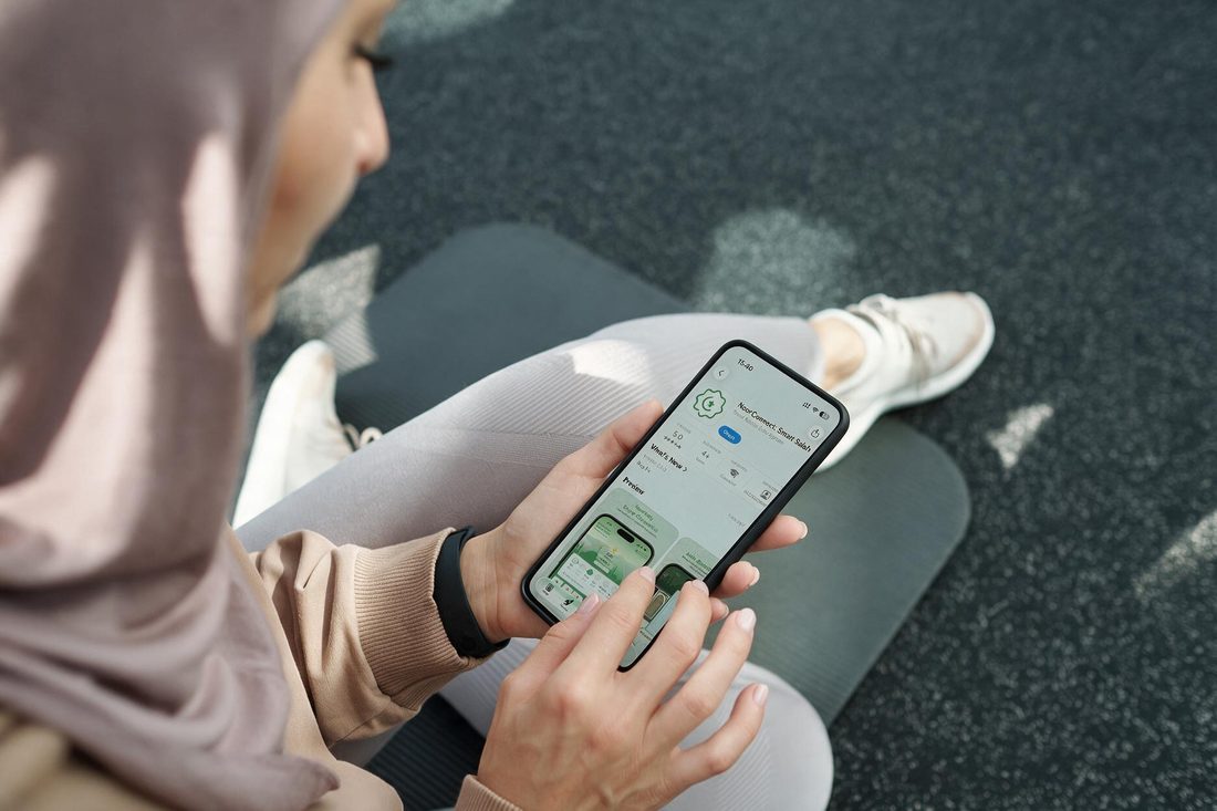 Phone held in hand showing the NoorConnect app listing with its latest updates
