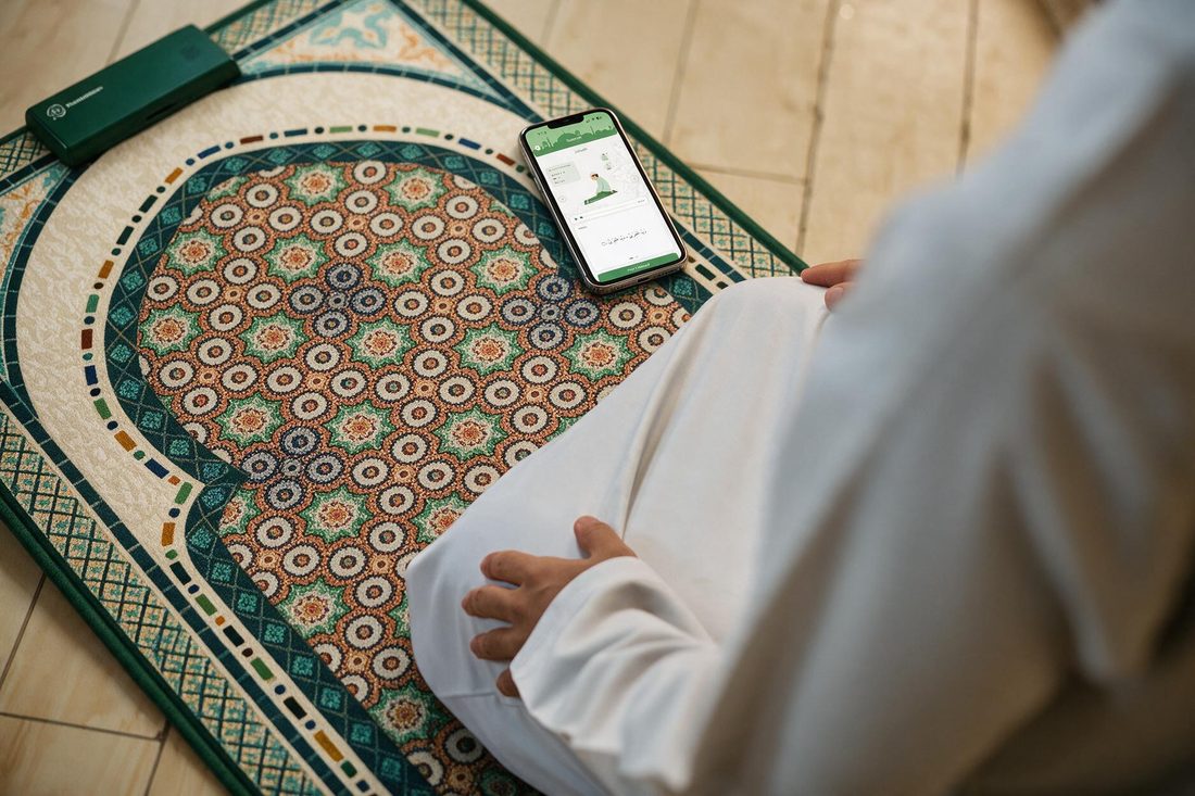 Person kneeling on the responsive prayer mat with the control module and a phone showing guided Salah