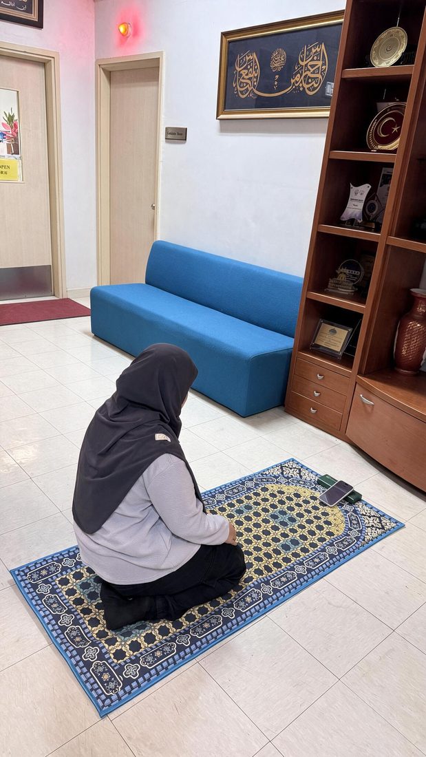 Woman praying on a NoorConnect responsive prayer mat with her phone beside her